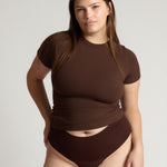 Woman wearing a brown top and bottom on a plain background