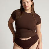 Woman wearing a brown top and bottom on a plain background