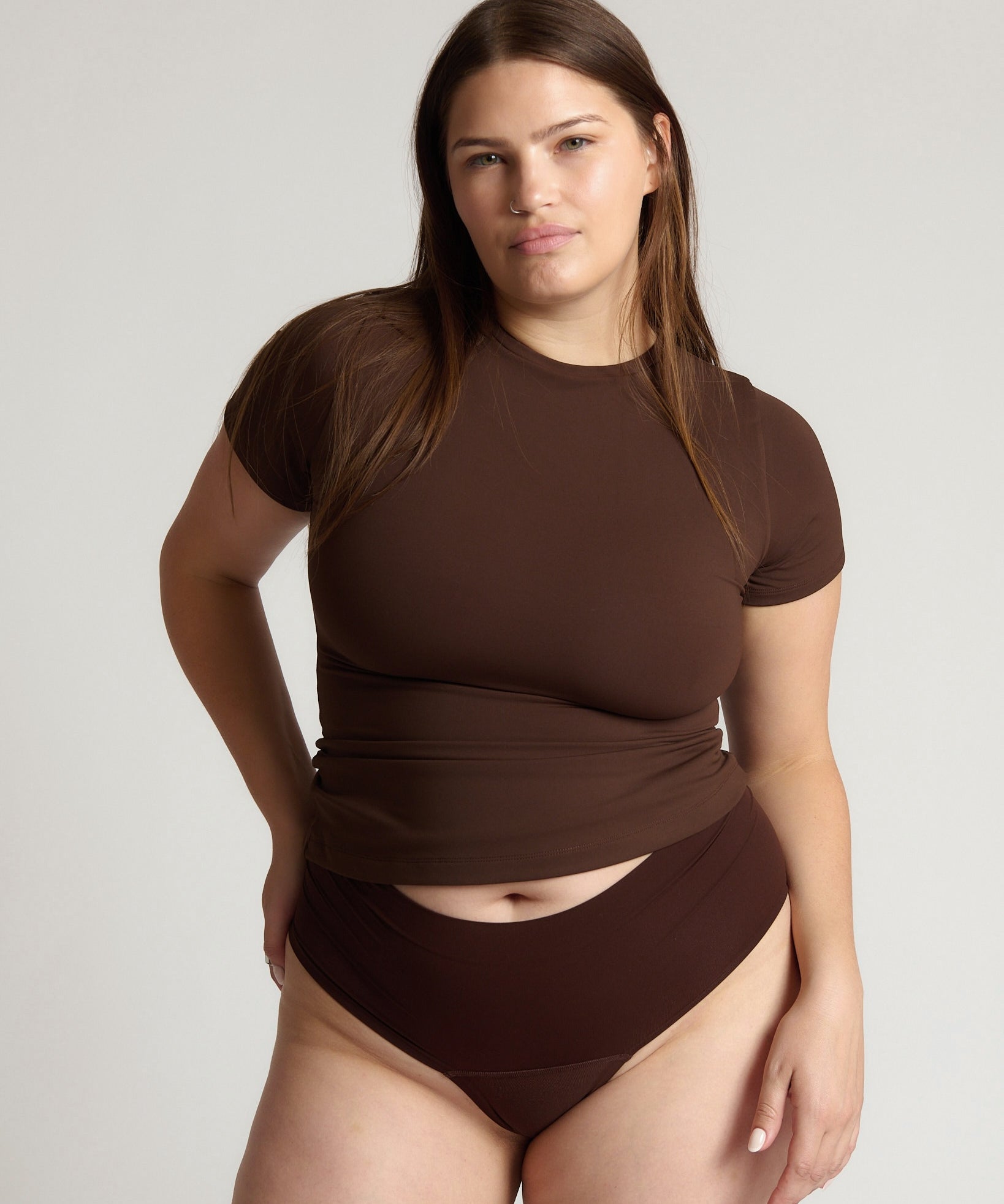 Woman wearing a brown top and bottom on a plain background