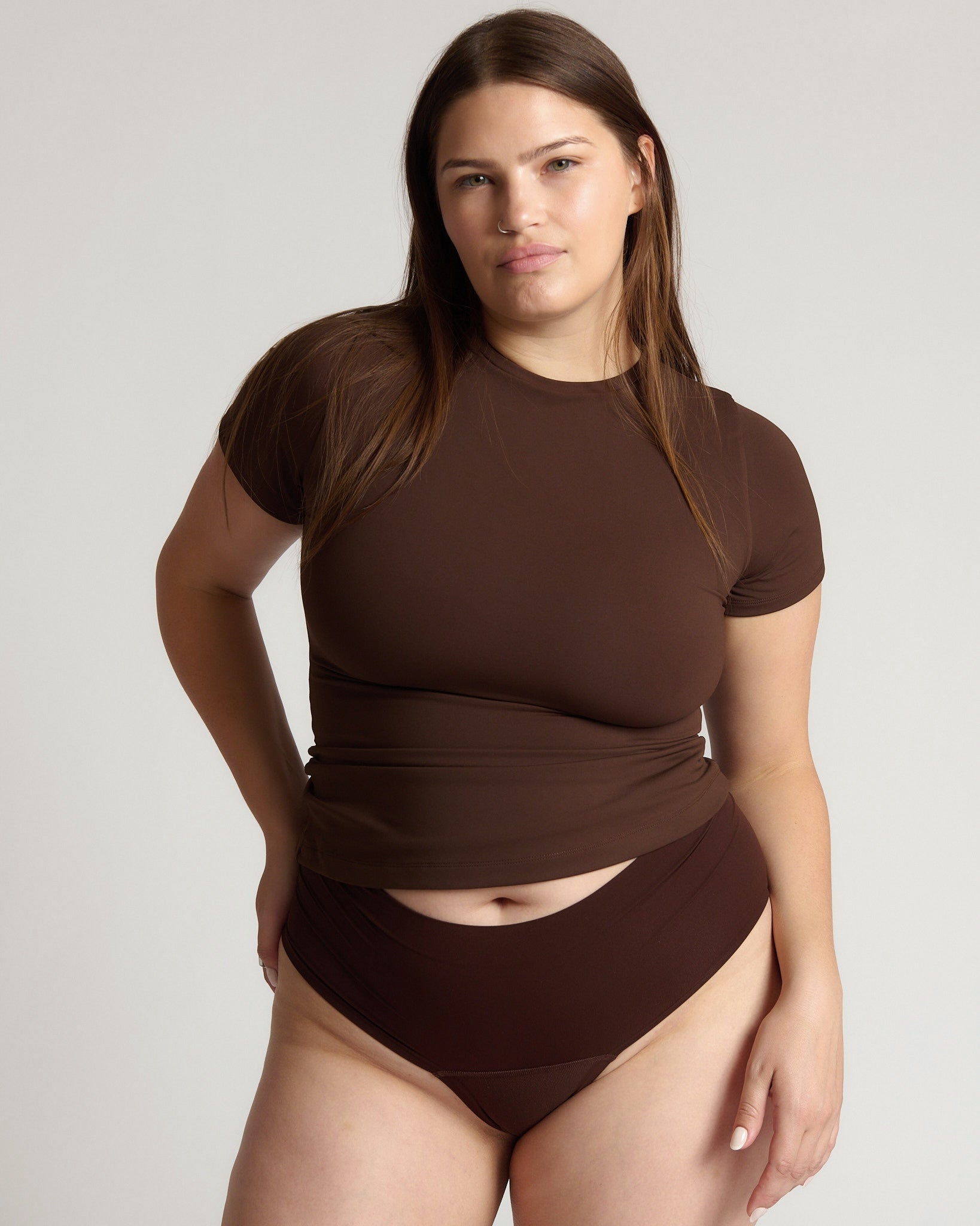 Woman wearing a brown top and bottom on a plain background