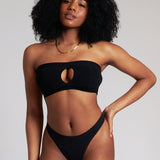 Woman wearing black strapless system against a neutral background