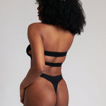 Woman wearing black strapless system against a neutral background