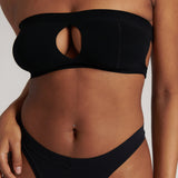 Woman wearing black strapless system against a neutral background