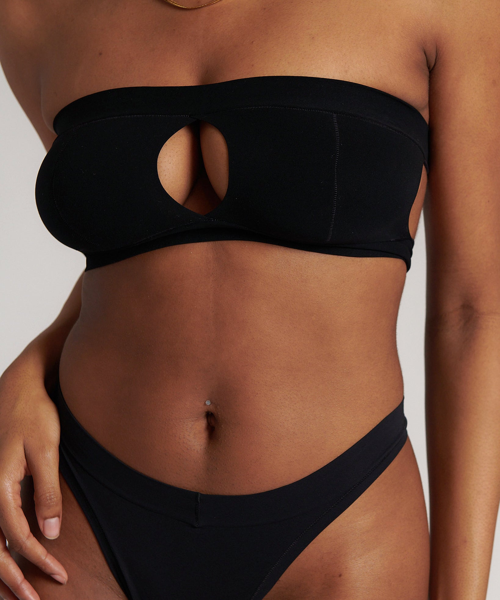 Woman wearing black strapless system against a neutral background