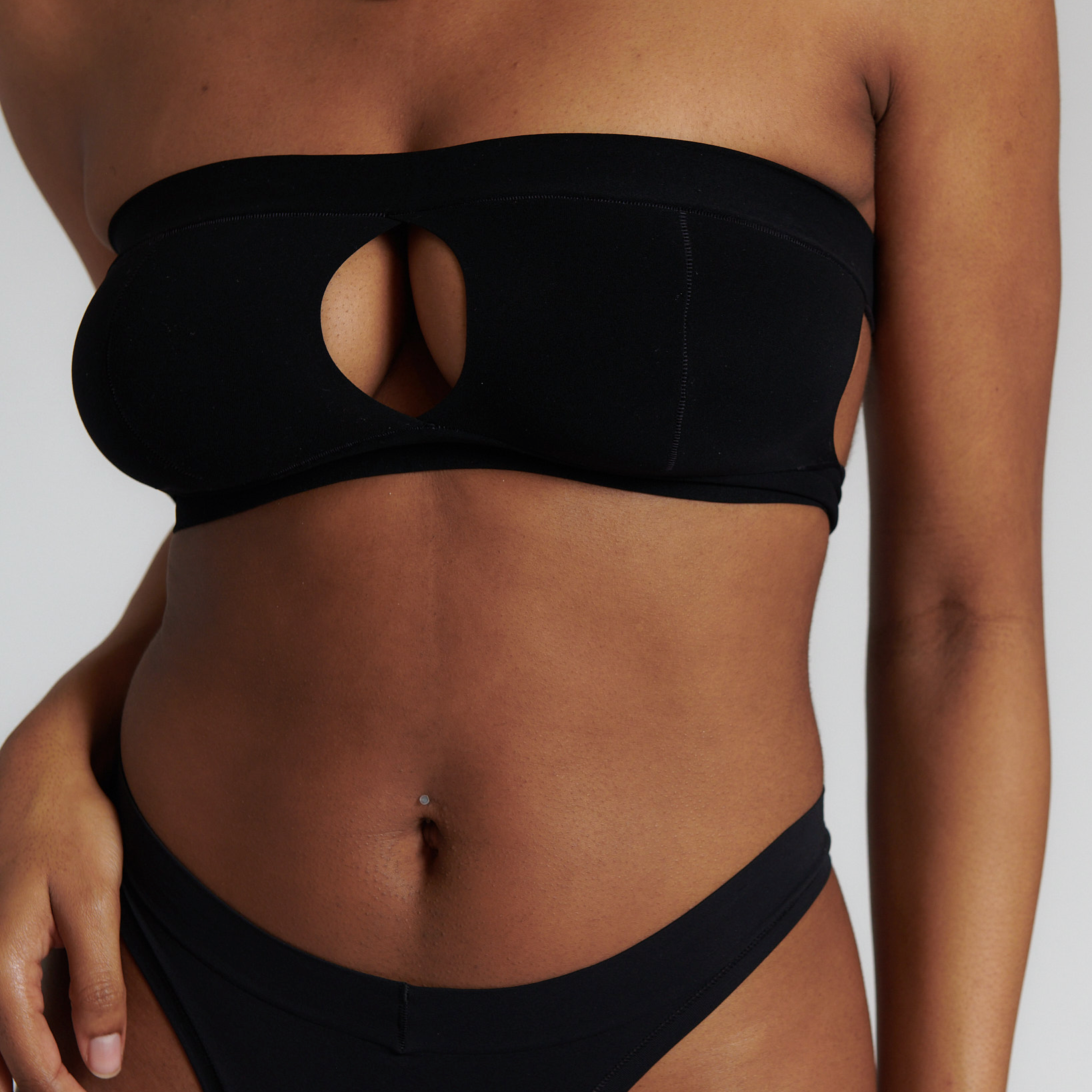 Woman wearing black strapless system against a neutral background