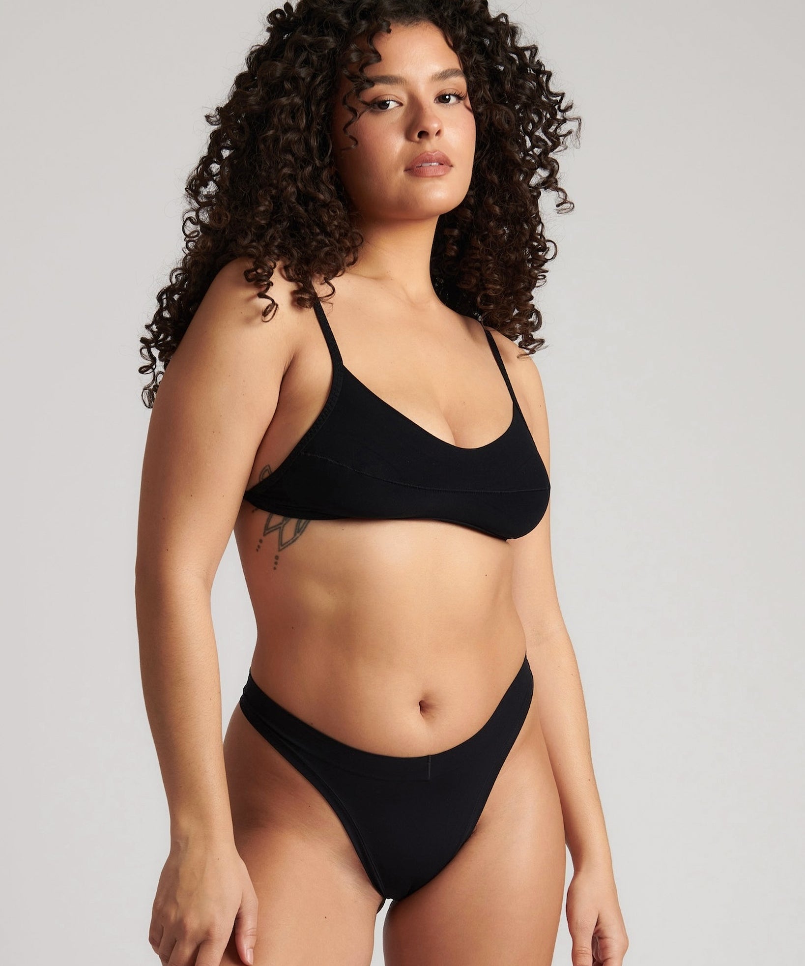 Woman wearing black scoop system against a neutral background