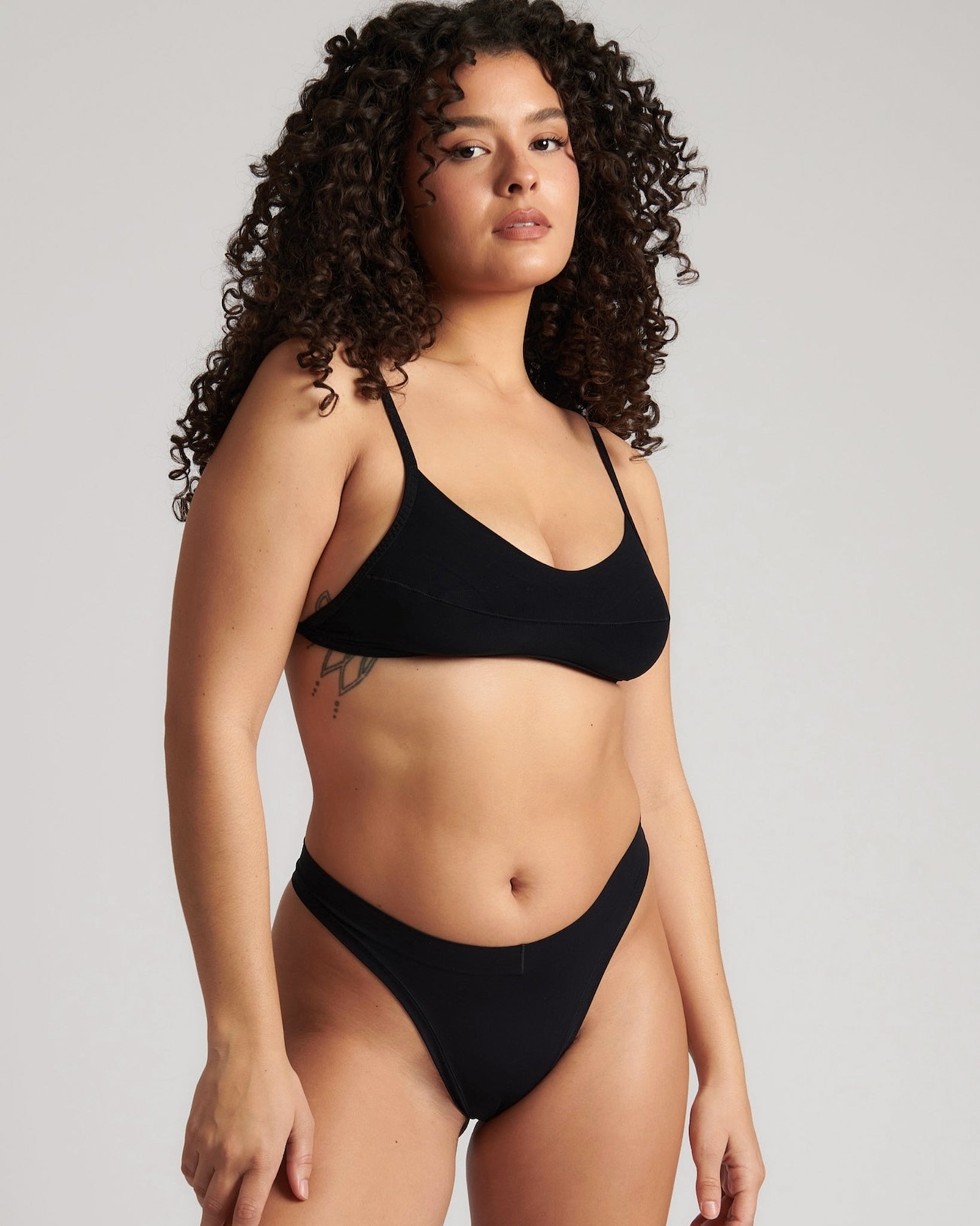 Woman wearing black scoop system against a neutral background