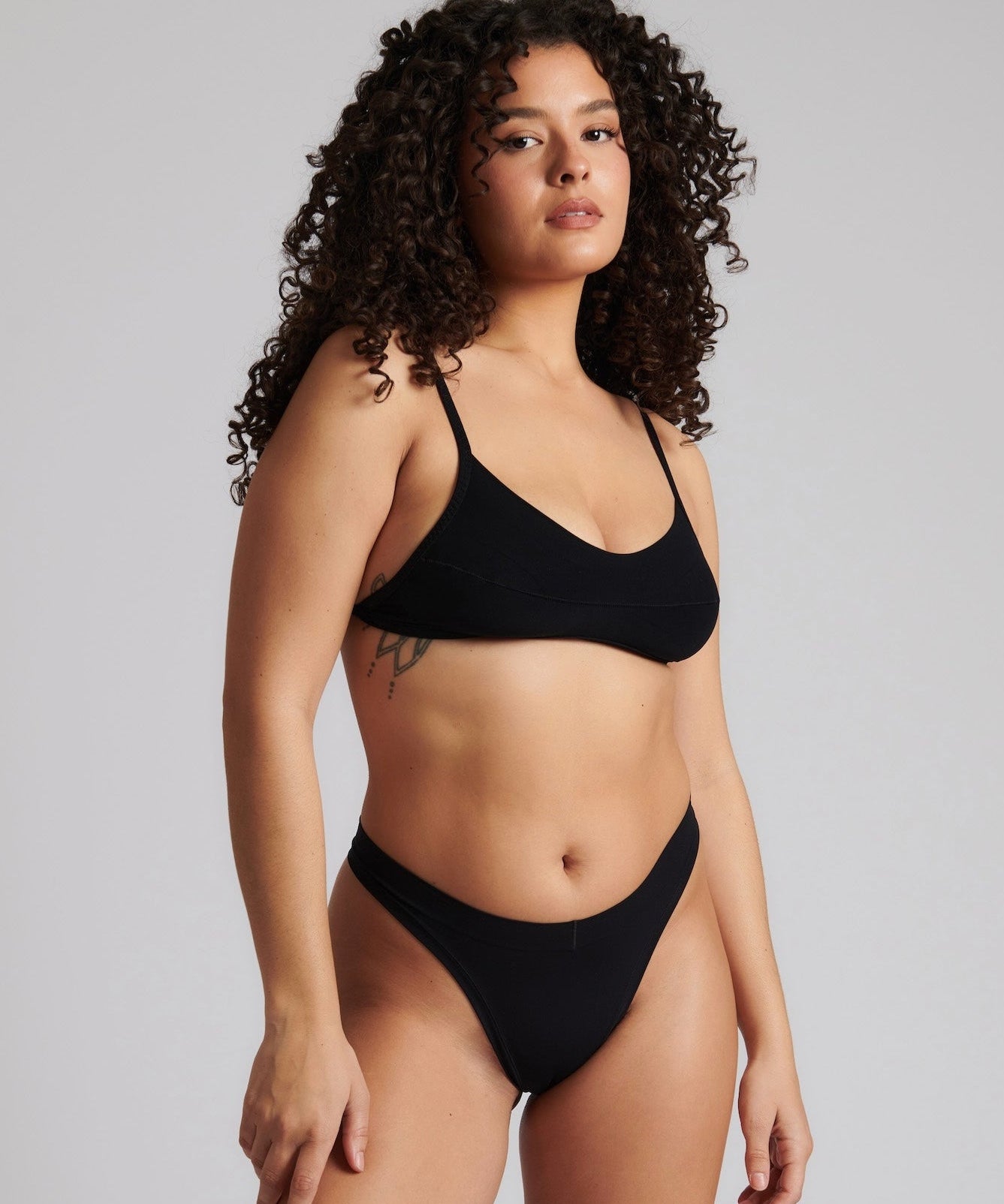 Woman wearing black scoop system against a neutral background