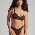 A person wearing a brown thong and scoop system on a plain background.