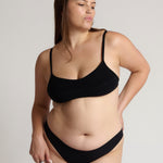 Woman wearing black scoop system against a neutral background