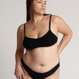 Woman wearing black scoop system against a neutral background