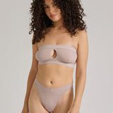 Woman wearing a beige strapless against a plain background