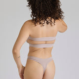 Woman wearing a beige strapless against a plain background