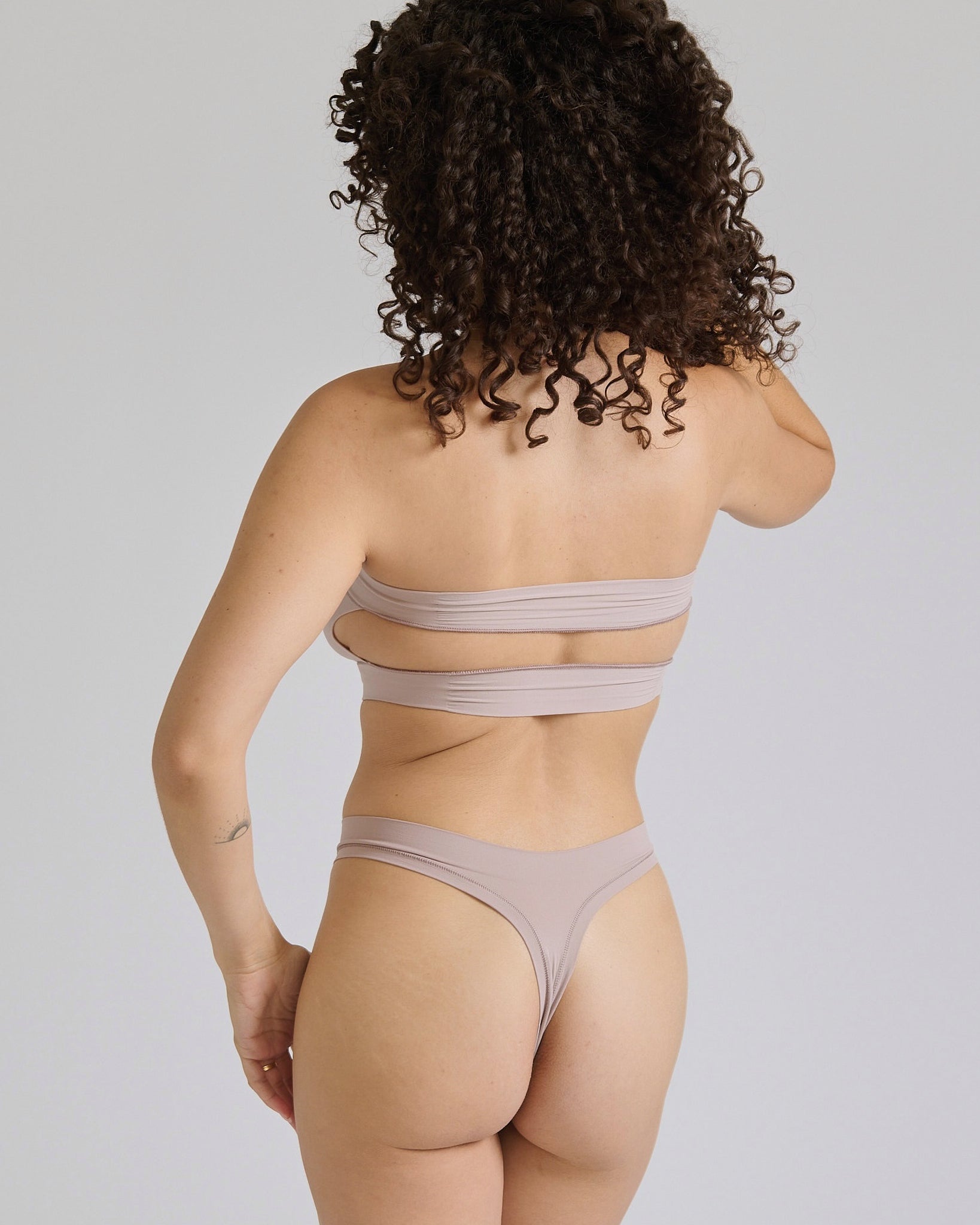 Woman wearing a beige strapless against a plain background