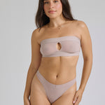 Woman wearing a beige strapless against a plain background