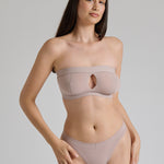 Woman wearing a beige strapless against a plain background