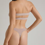 Woman wearing a beige strapless against a plain background