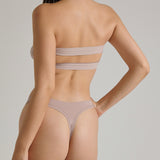 Woman wearing a beige strapless against a plain background