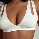 A person wearing a white, solid-colored bra and matching thong, with unique strap details and a v-neckline.