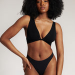 A woman is wearing a black twist system and thong