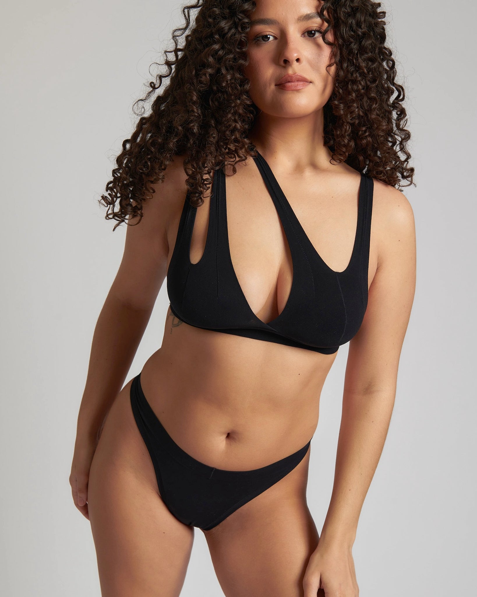 Woman wearing black tee system on plain background