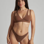 Woman wearing a brown bra against a neutral background