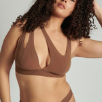 Woman wearing a brown bra against a neutral background