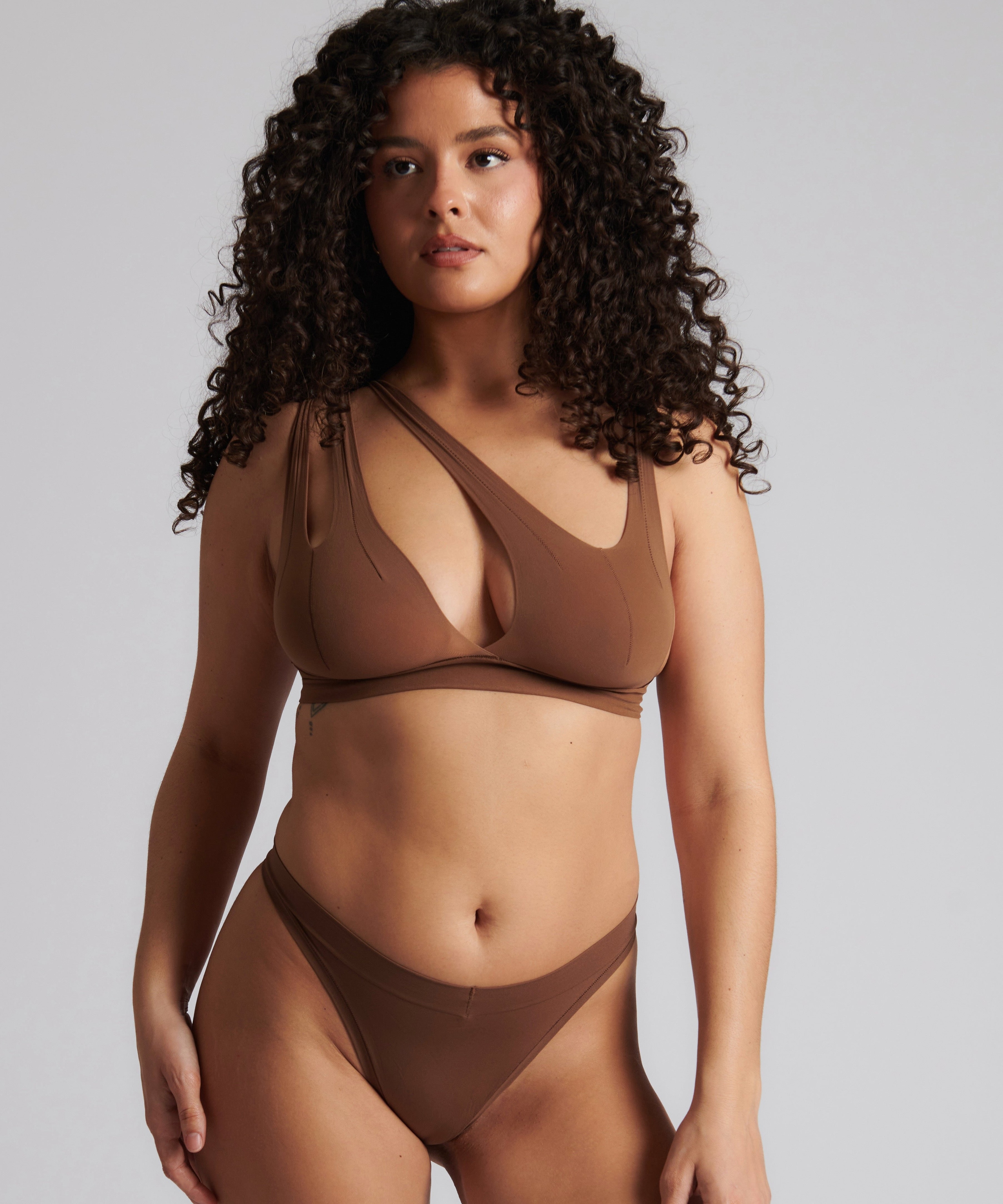 Woman wearing a brown bra against a neutral background