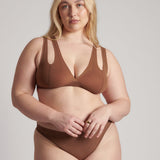 Woman wearing a brown bra against a neutral background