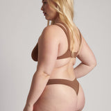 Woman wearing a brown bra against a neutral background