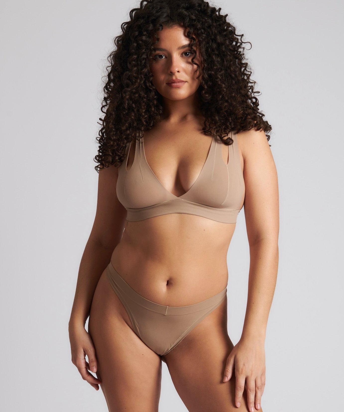 Woman wearing a light bra and matching thong with a deep v-neckline.