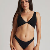 A woman is wearing a black twist system and thong