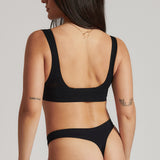 A woman is wearing a black twist system and thong