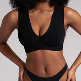A woman wearing a black minimalist bra with wide straps and a deep neckline.