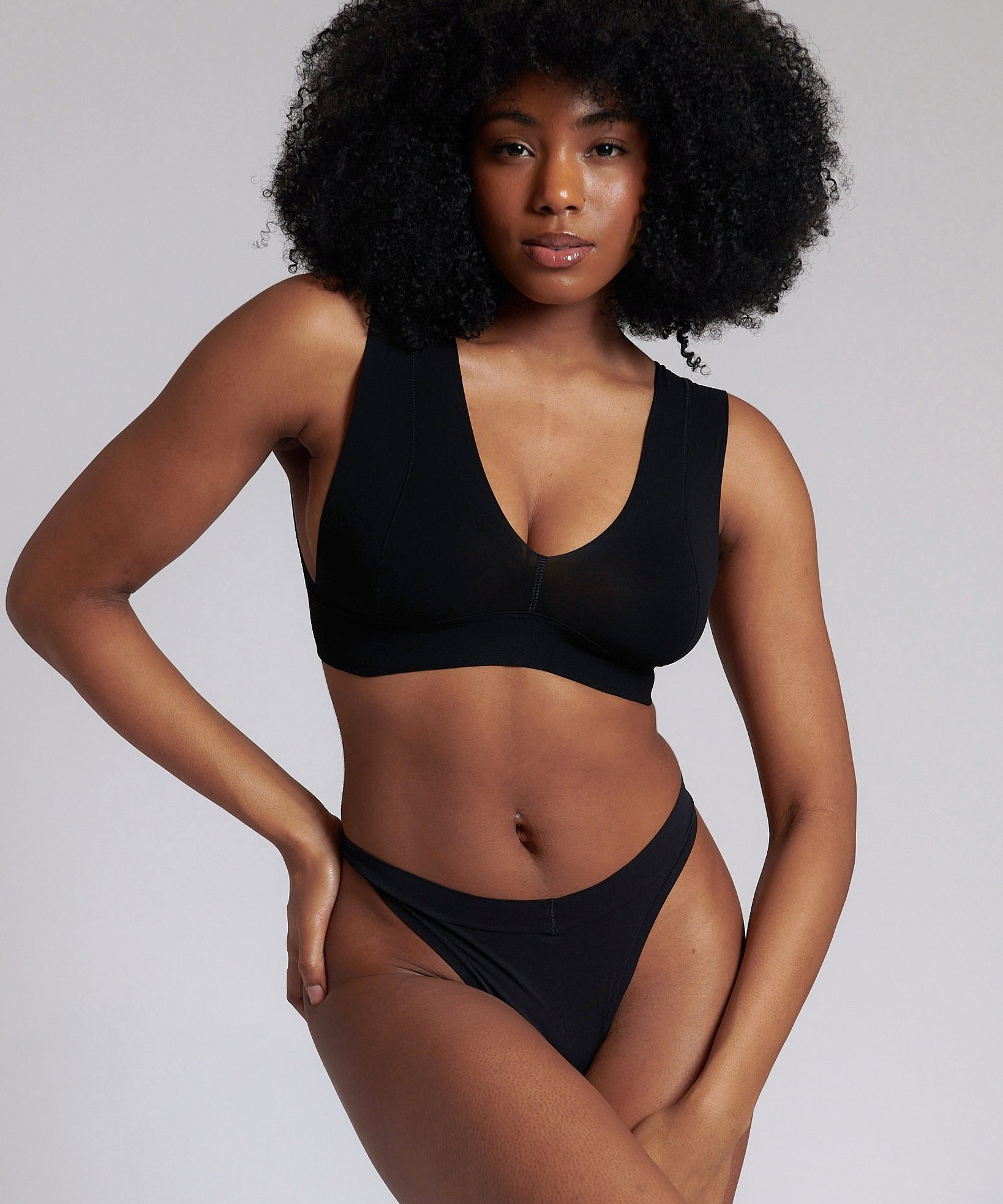 A woman wearing a black minimalist bra with wide straps and a deep neckline.