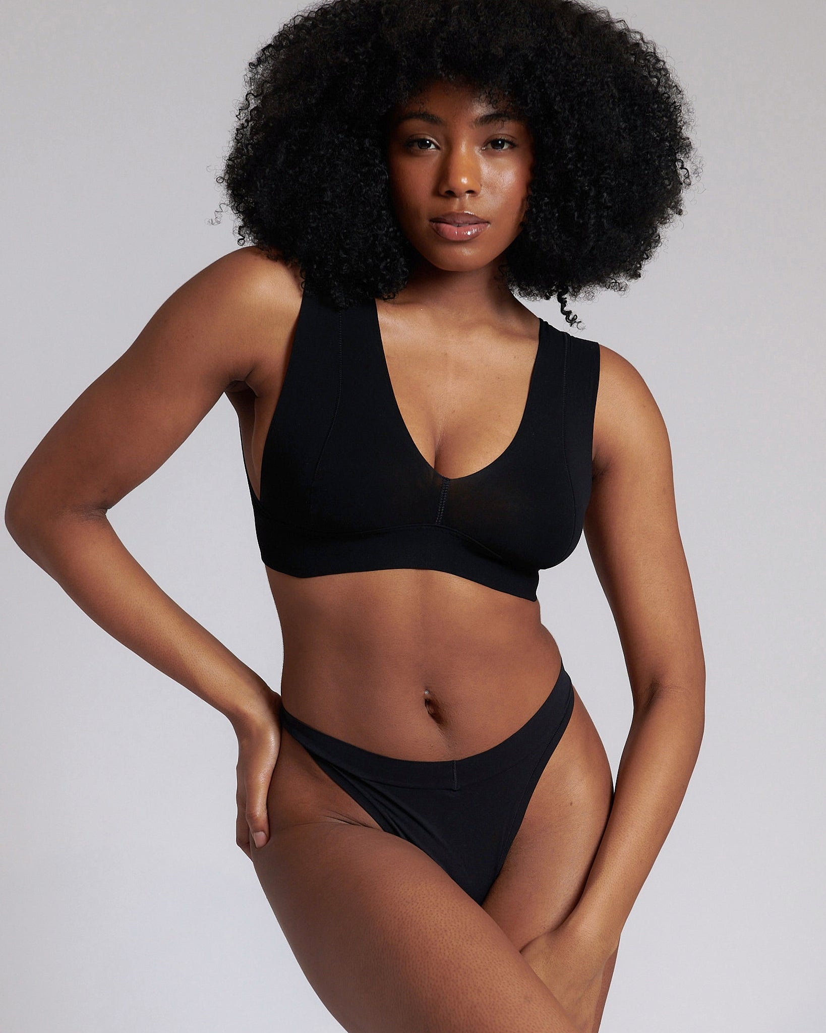 A woman wearing a black minimalist bra with wide straps and a deep neckline.