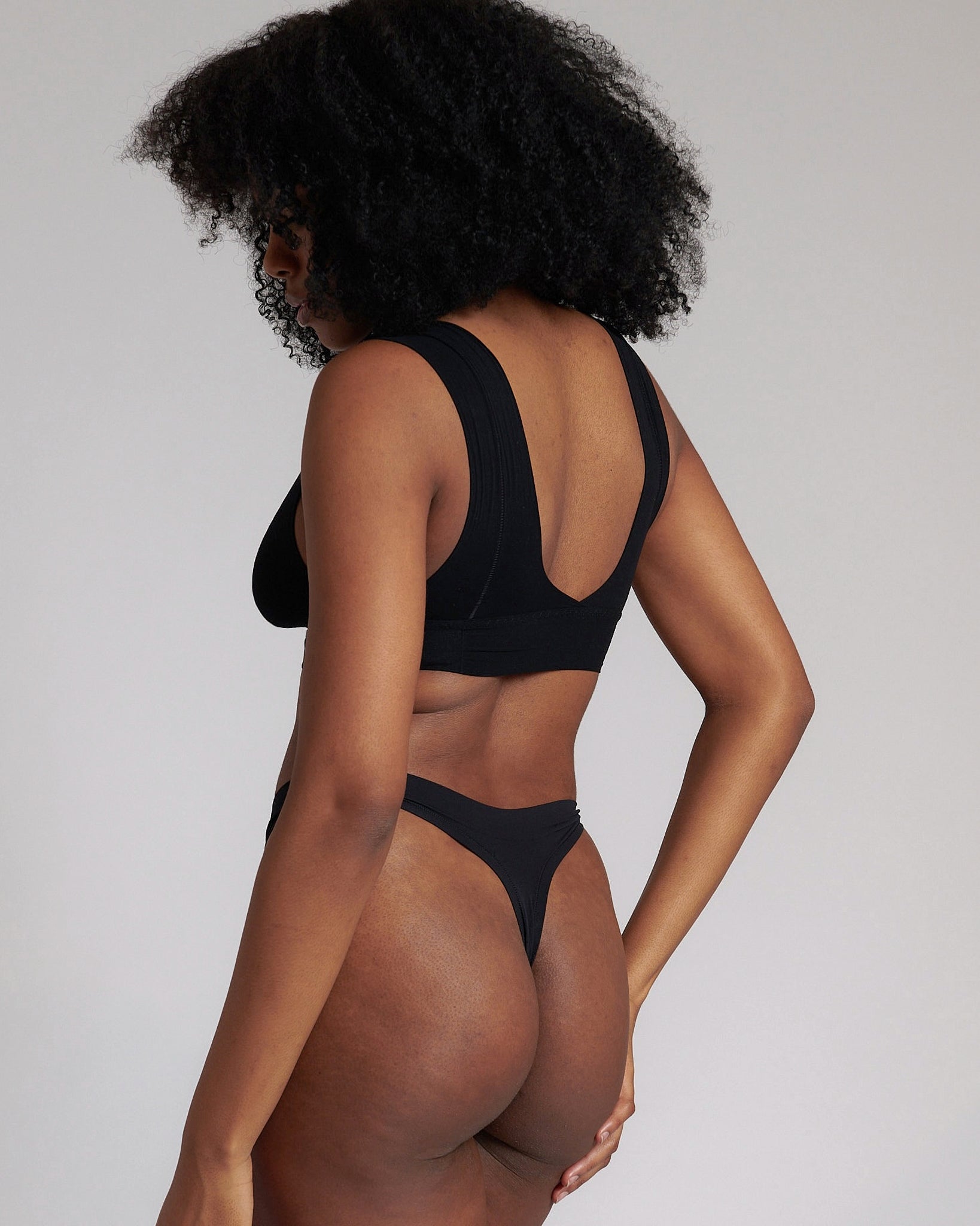 A woman wearing a black minimalist bra with wide straps and a deep neckline.