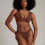 Woman wearing a brown underwear set against a neutral background