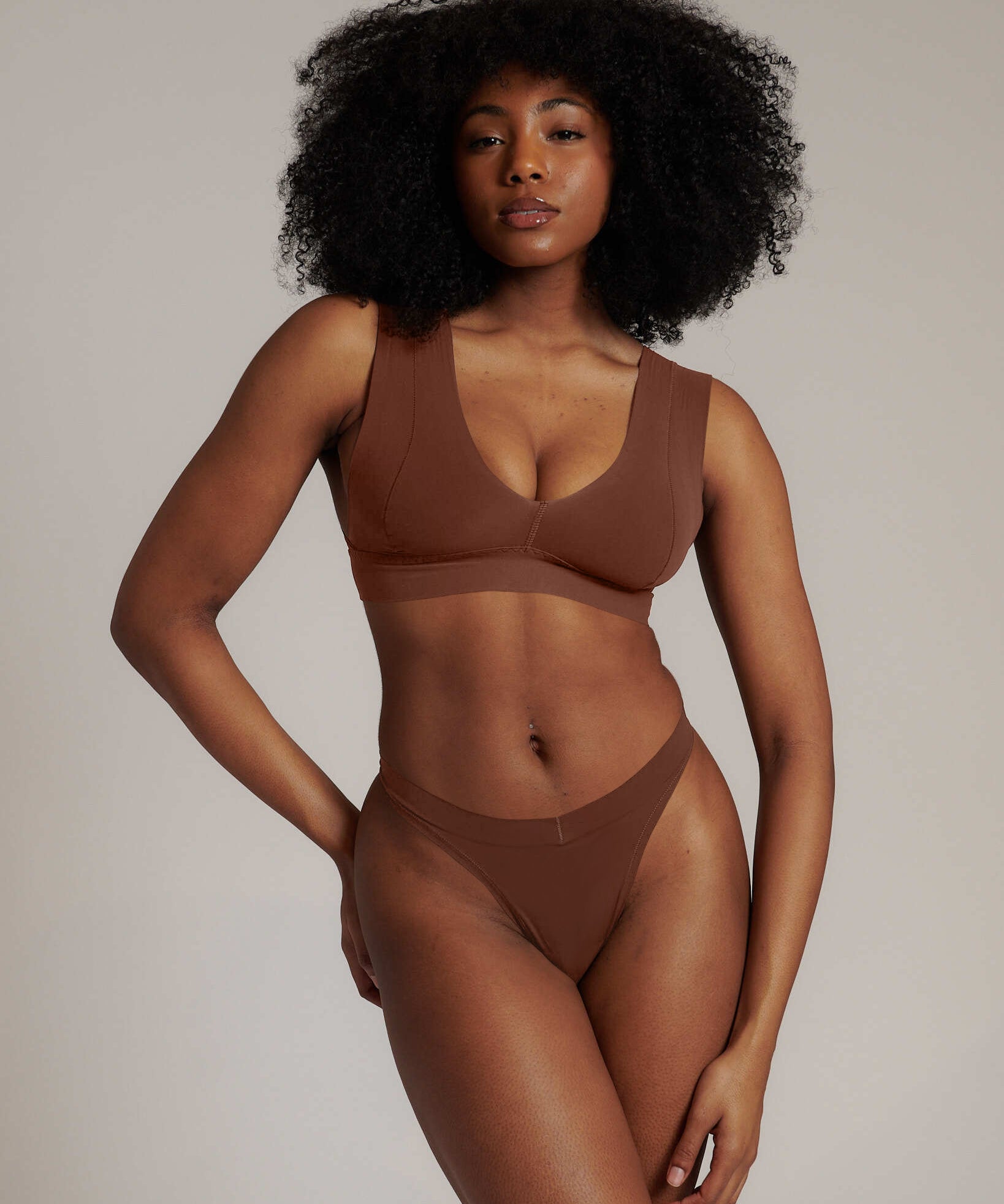 Woman wearing a brown underwear set against a neutral background