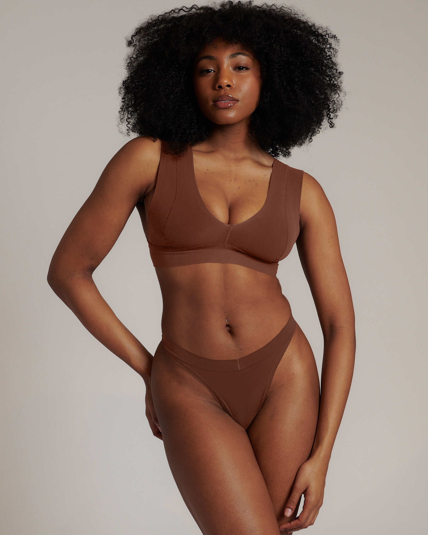 Woman wearing a brown underwear set against a neutral background