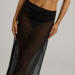 Woman wearing a black sheer dress against a plain background