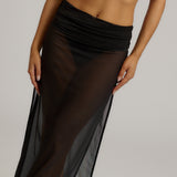Woman wearing a black sheer dress against a plain background