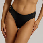 Person wearing black high-waisted bikini bottoms on a neutral background