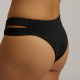 Person wearing black high-waisted bikini bottoms on a neutral background