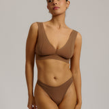 Woman wearing a brown bra against a plain background