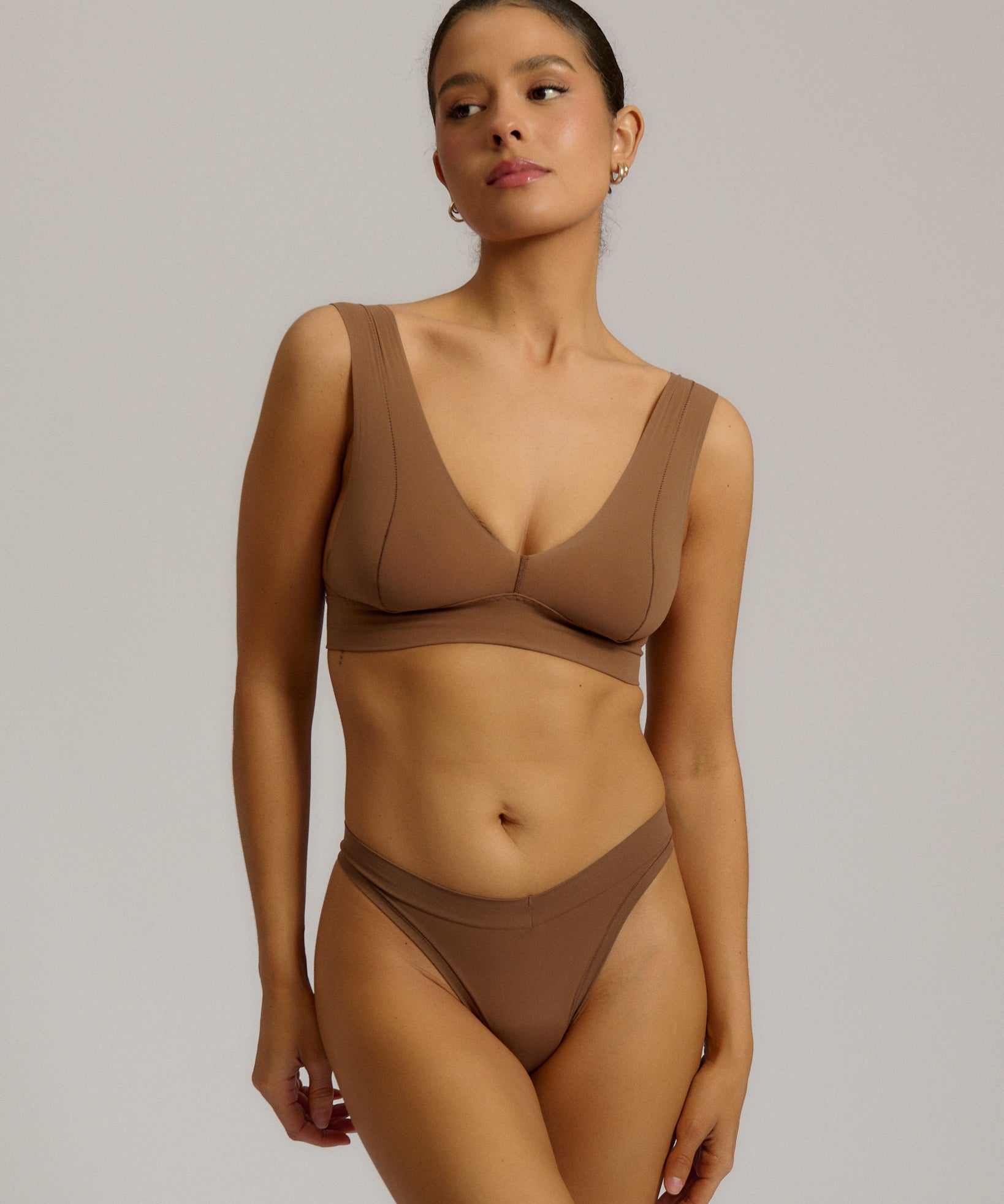 Woman wearing a brown bra against a plain background