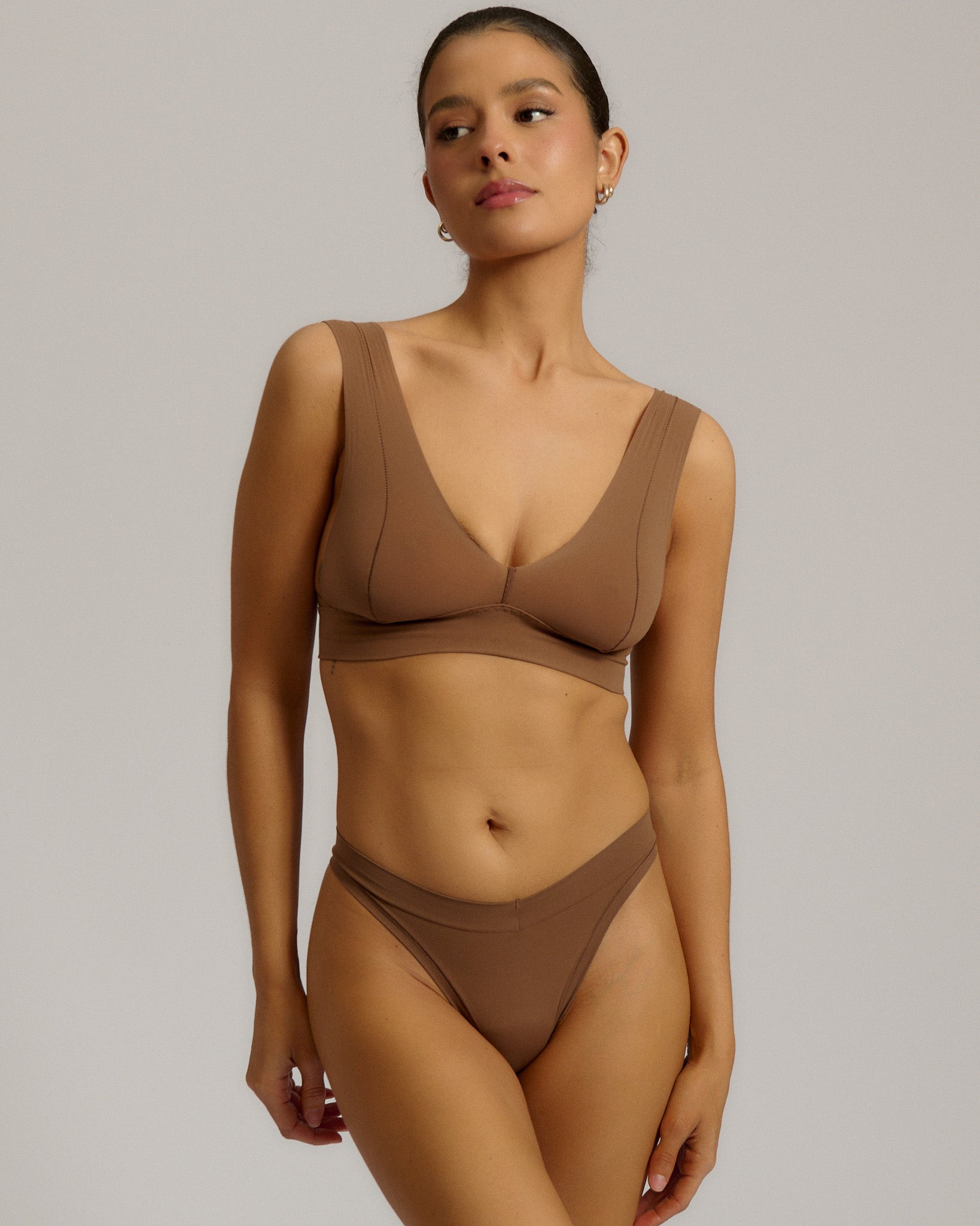 Woman wearing a brown bra against a plain background