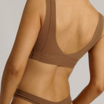 Woman wearing a brown bra against a plain background