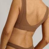 Woman wearing a brown bra against a plain background