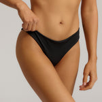 Person wearing a black bikini bottom against a neutral background